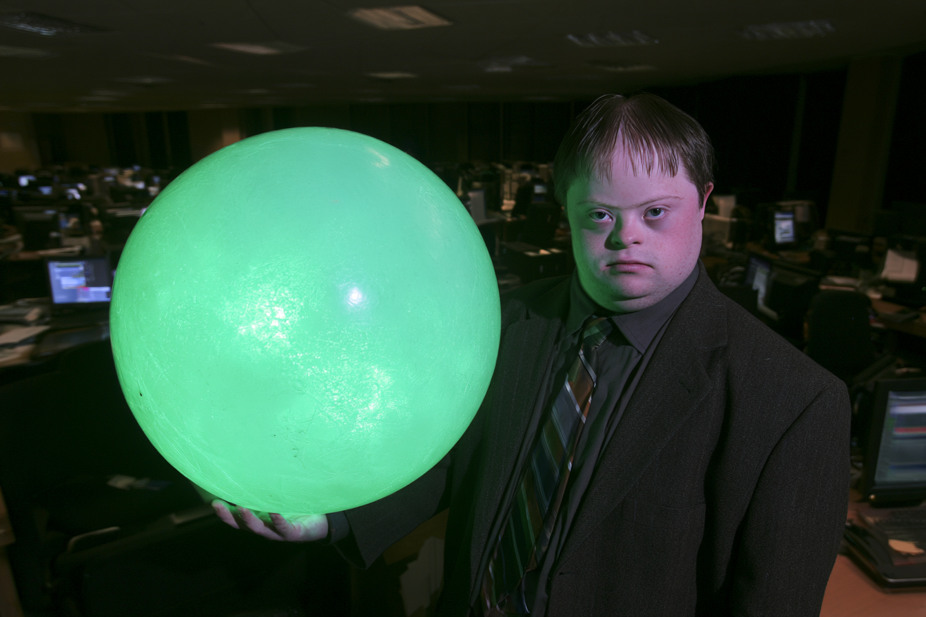 A person in a suit holding a glowing green orb in an office